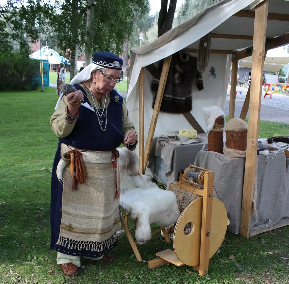 Femme en costume médiéval filant la laine sur un marché historique