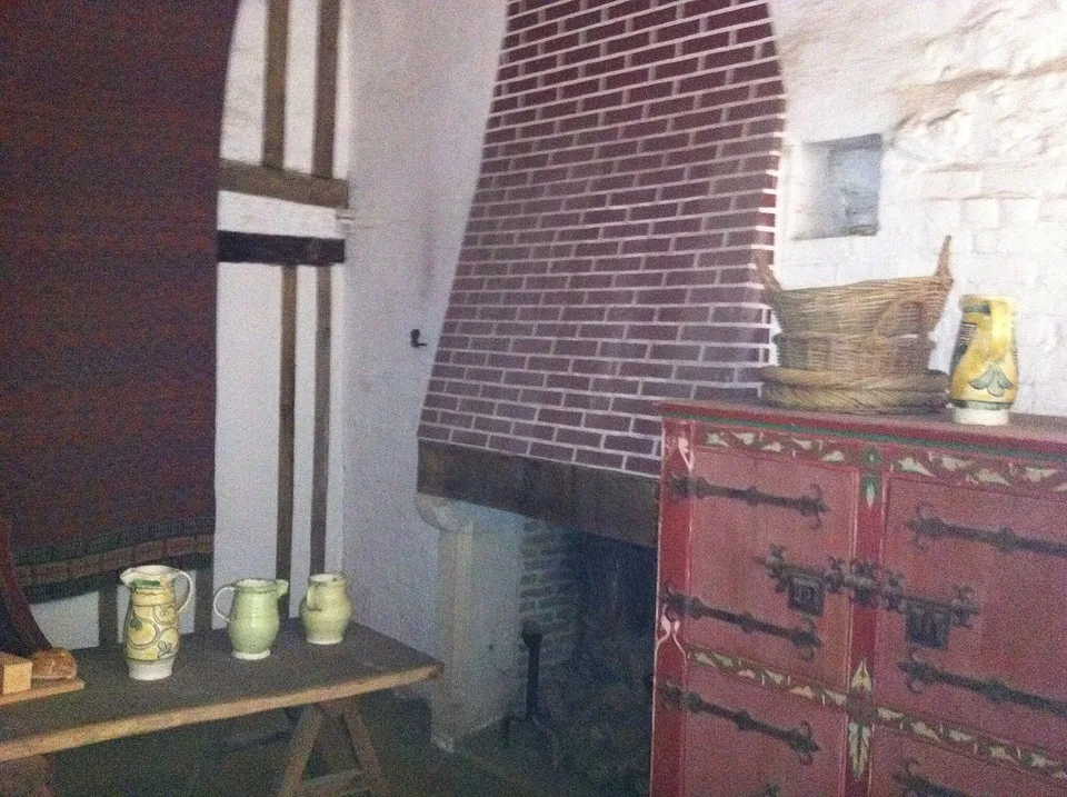 Pièce principale d’une maison médiévale en torchis et bois avec mobilier rustique