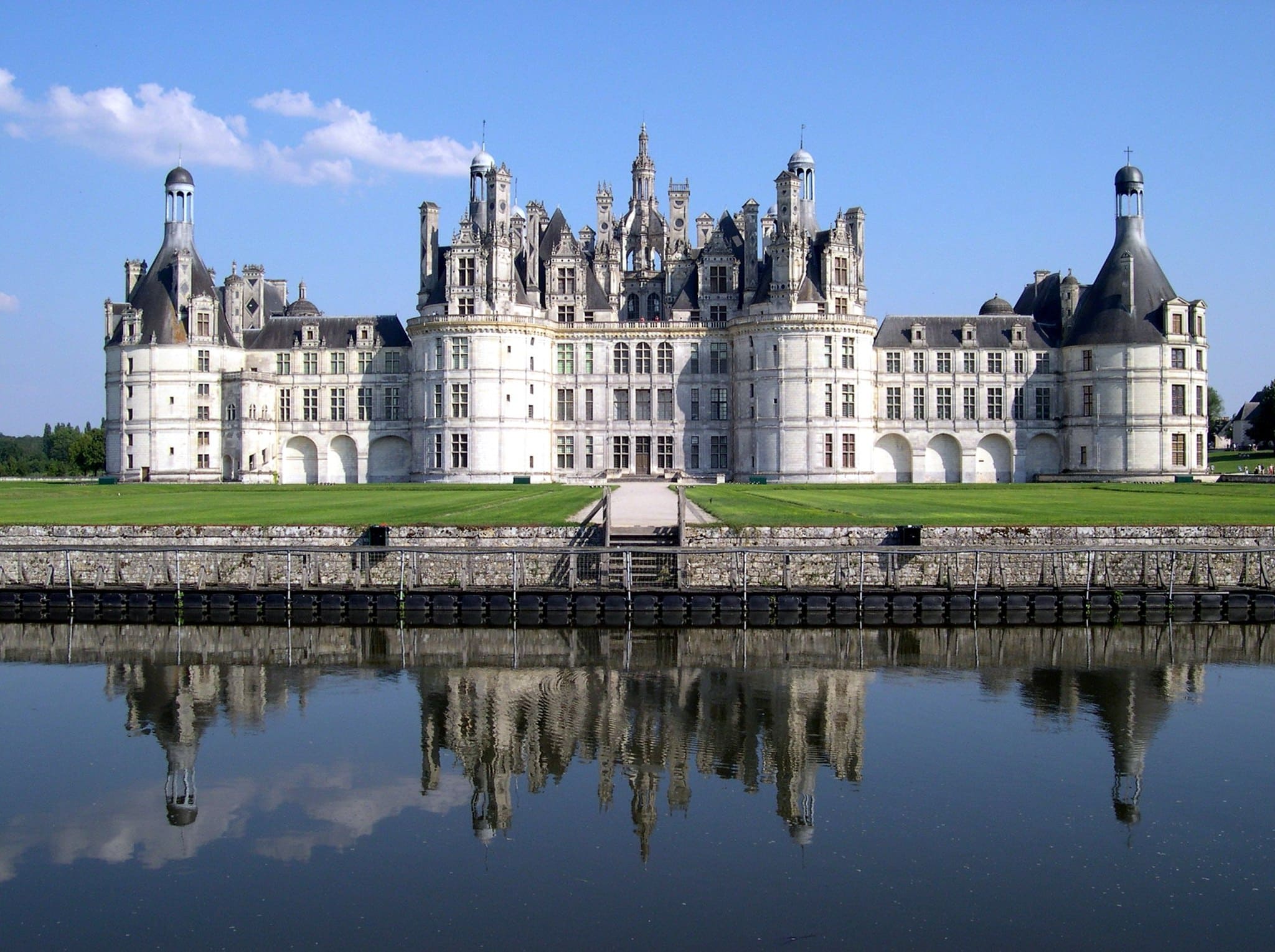 Façade symétrique du château de Chambord avec ses tours et son reflet dans l’eau