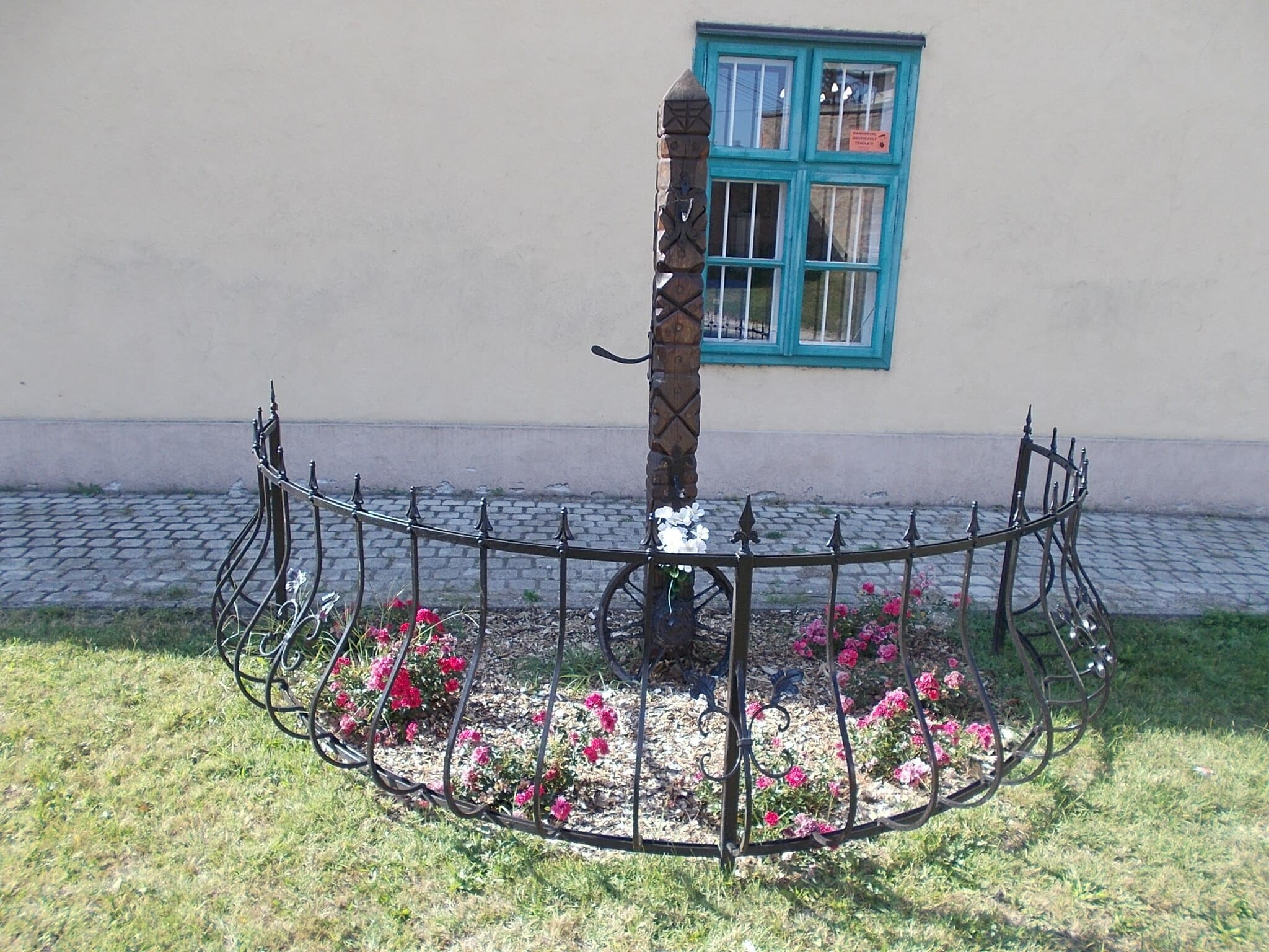Stèle en bois sculpté entourée d’une grille, dédiée à la mémoire des victimes roms et sintis du nazisme