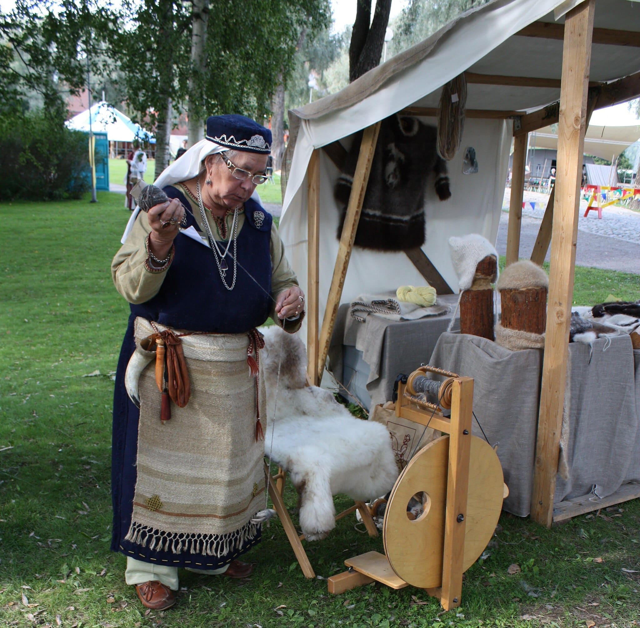 Femme en costume médiéval filant la laine sur un marché historique
