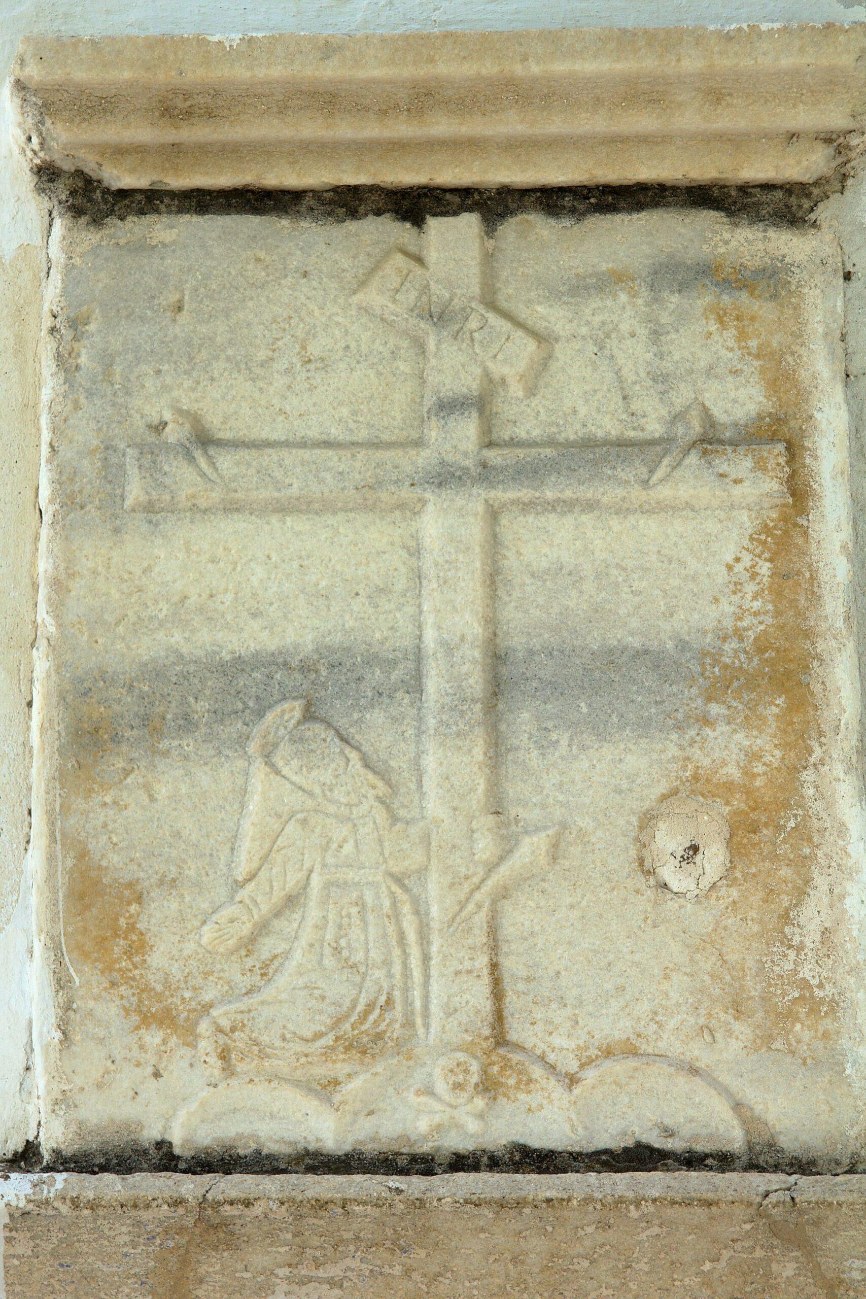 Bas-relief médiéval représentant une croix et un saint en prière