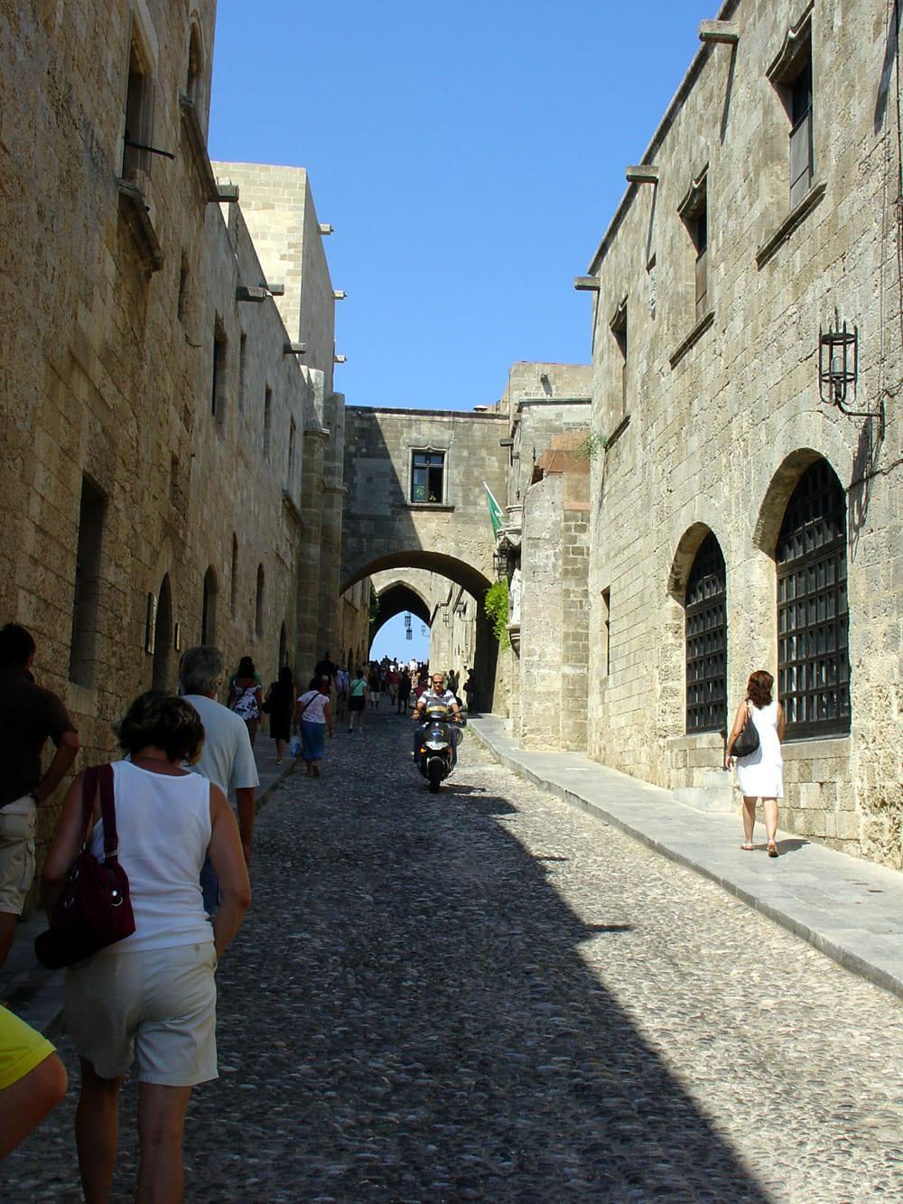 Rue pavée médiévale bordée de bâtiments en pierre à Rhodes